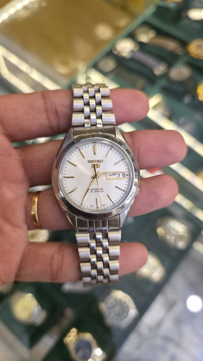 Seiko 5 Automatic watch featuring a silver-tone stainless steel bracelet and a white textured dial with gold-tone indices.