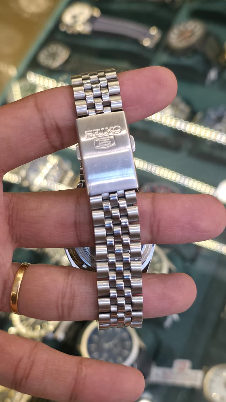 Seiko 5 Automatic watch featuring a silver-tone stainless steel bracelet and a white textured dial with gold-tone indices.