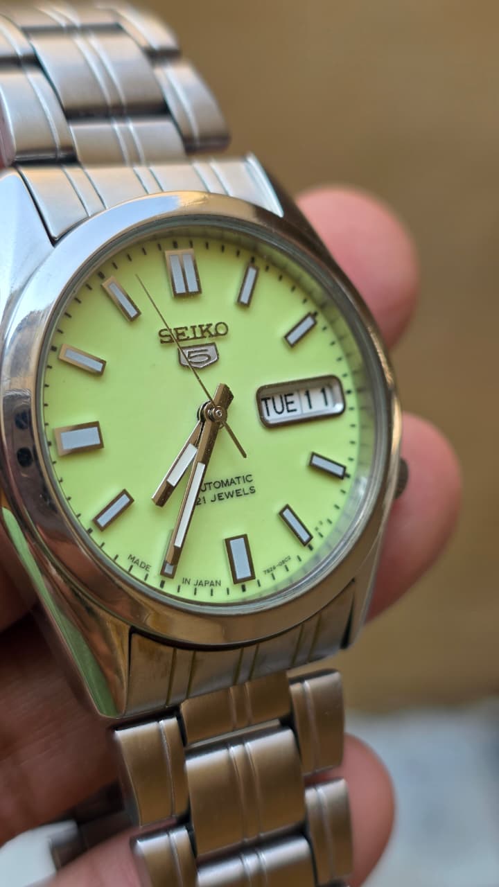 Seiko 5 automatic men's watch with a bright, full-lume yellow-green dial and stainless steel bracelet.