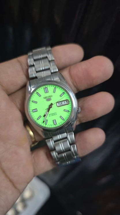 Seiko 5 automatic men's watch with a bright, full-lume yellow-green dial and stainless steel bracelet.